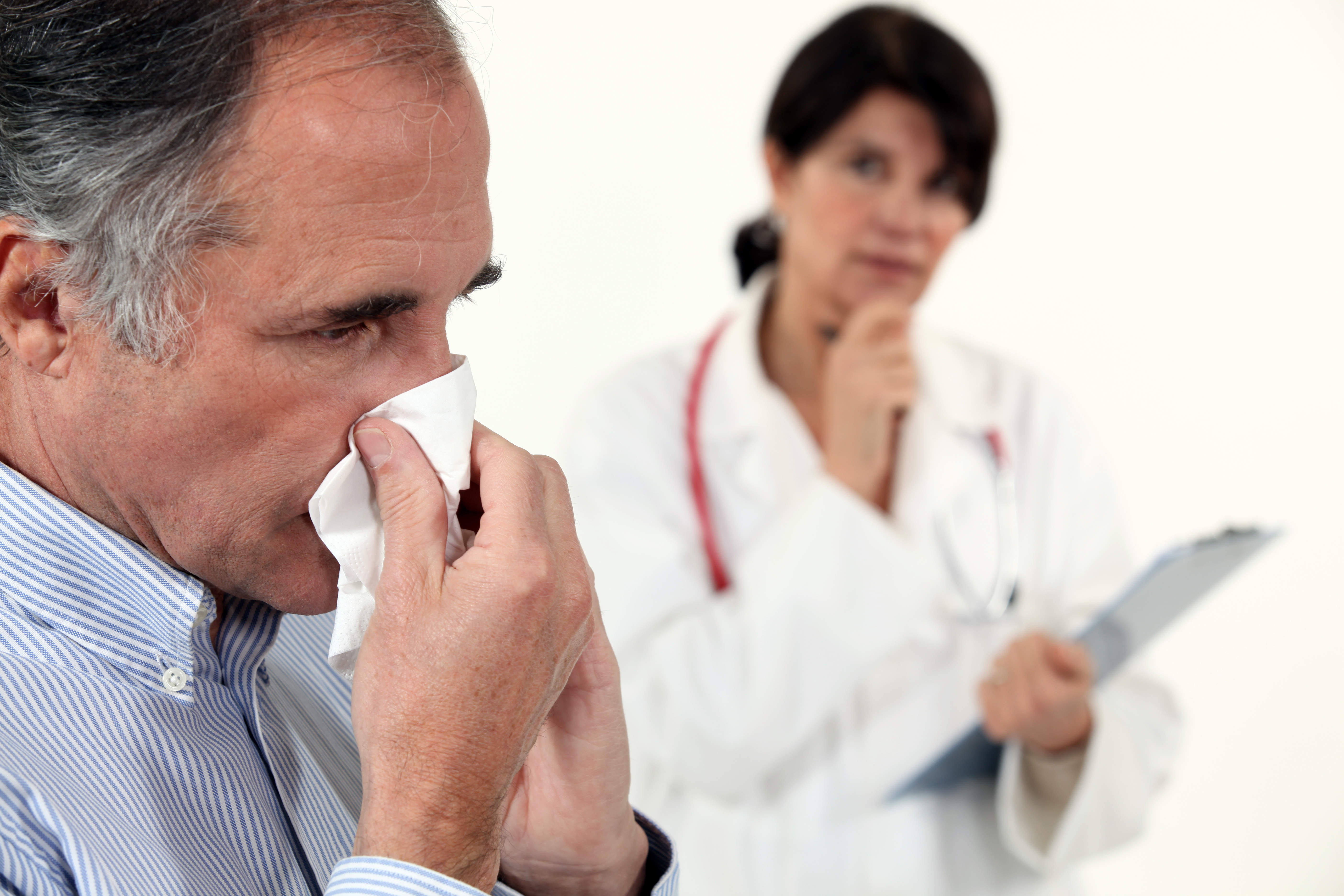 Man blowing his nose next to a doctor