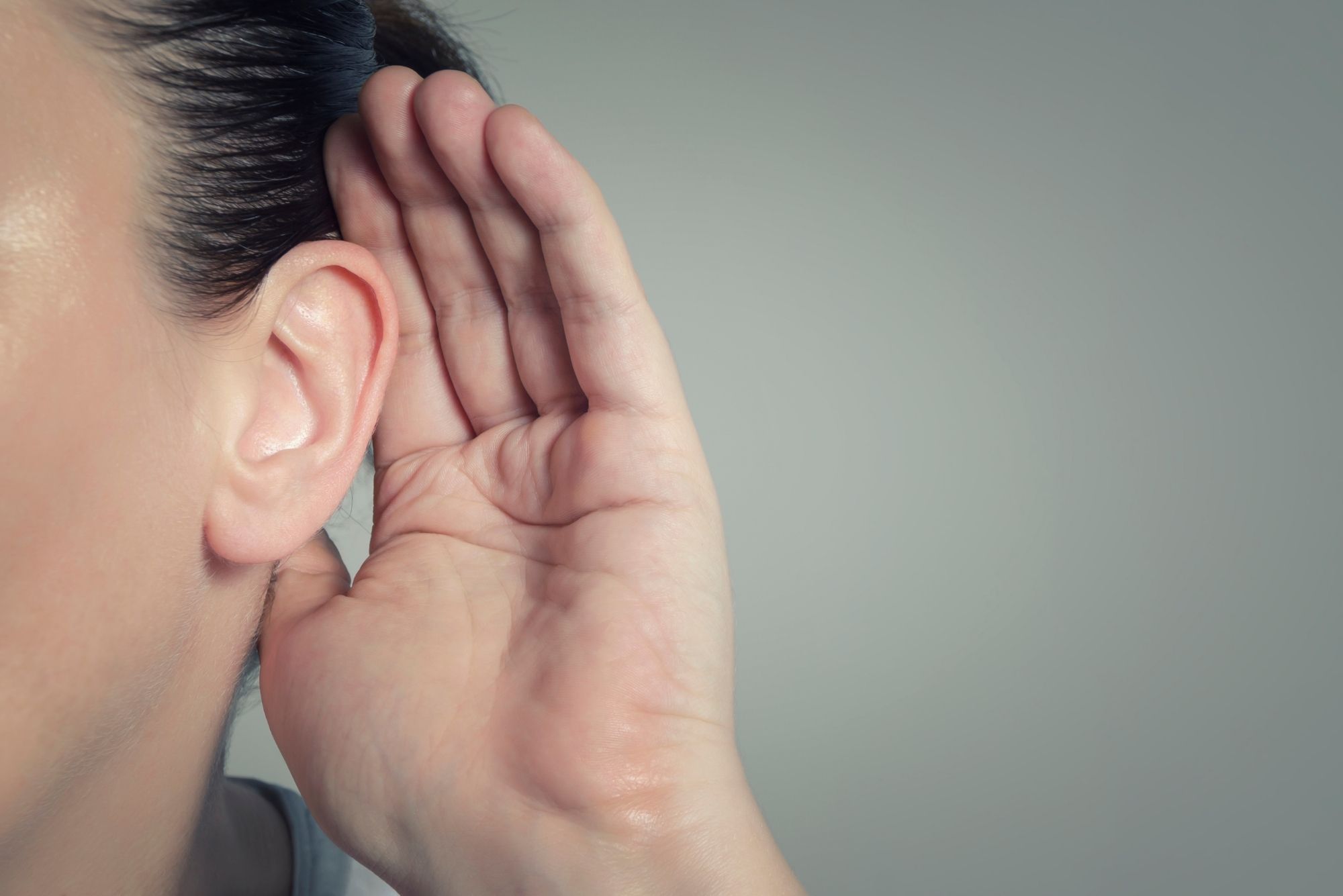 A woman holds her hand up to her ear as her ear tubes drain.