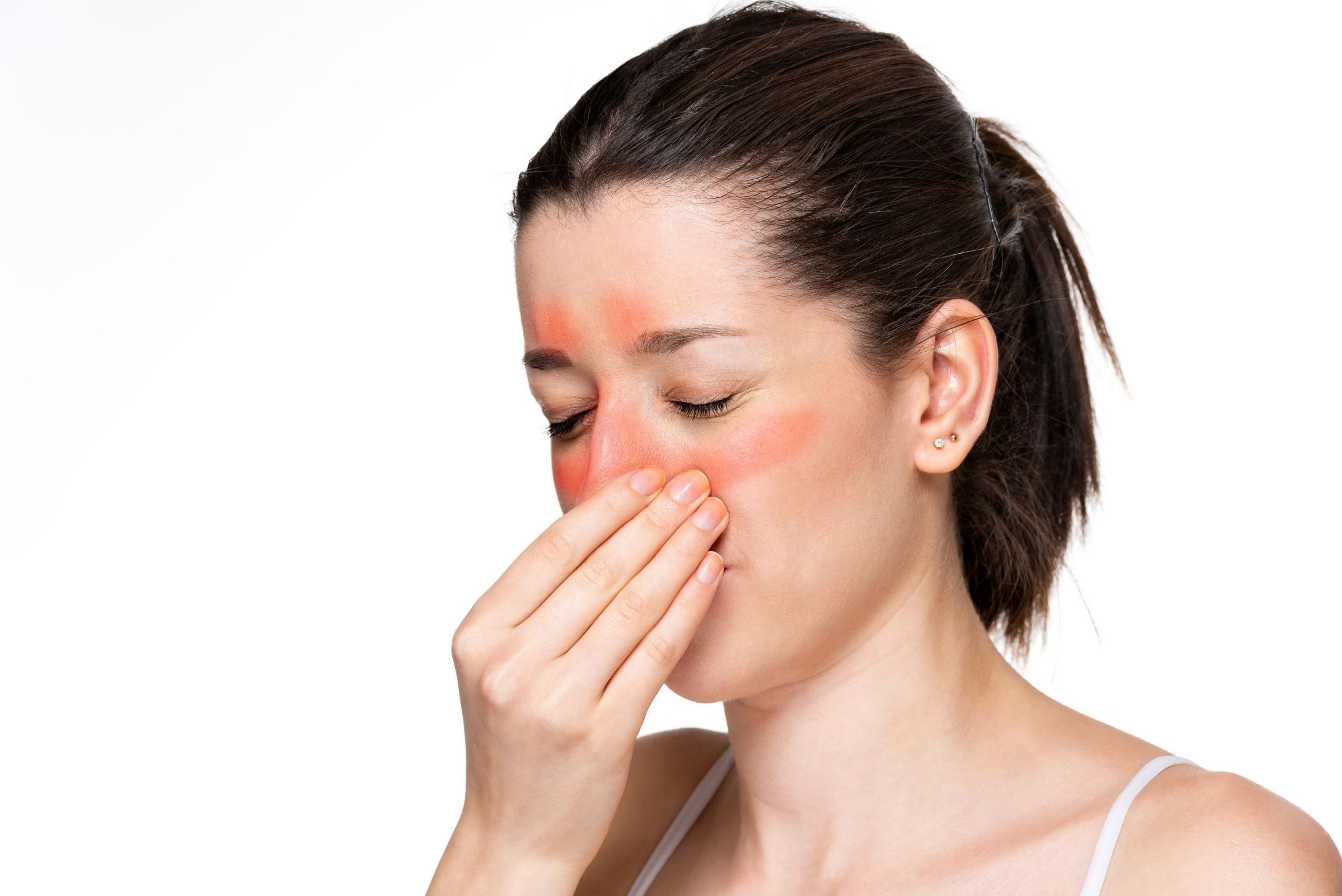 A woman closes her eyes and touches her nose while areas of her face are highlighted in red to represent sinus issues.