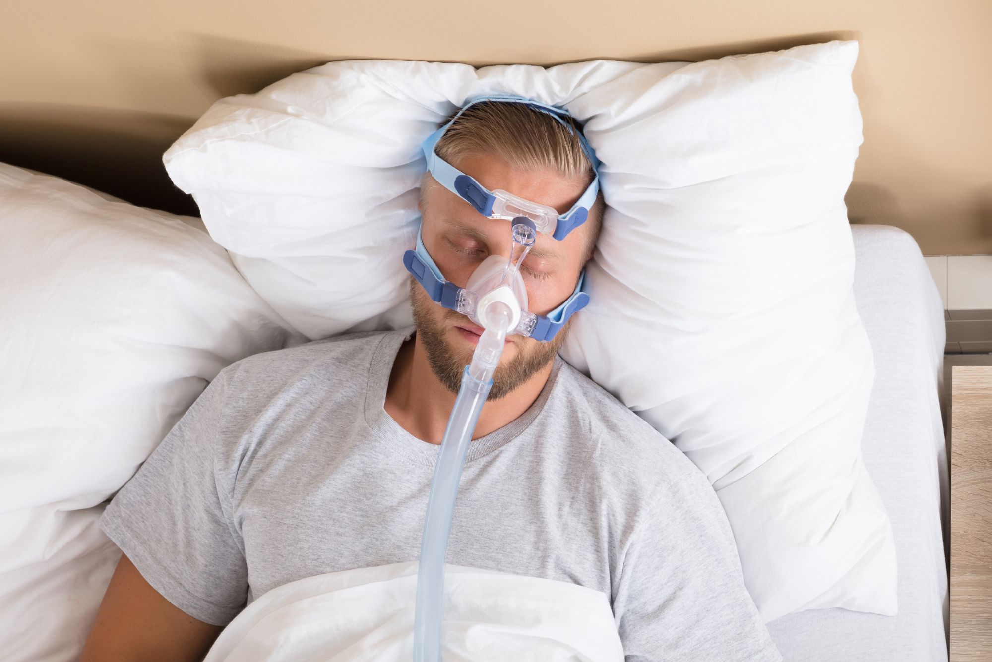 A man sleeping in bed with a CPAP machine, struggling with sleep apnea.