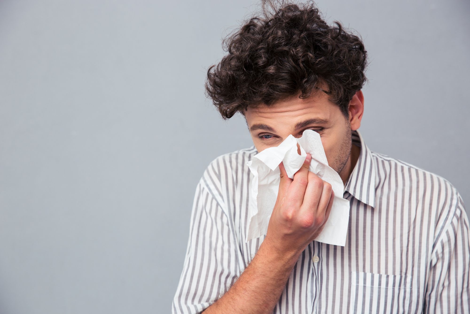 A person blowing their nose that is plugged with mucus.