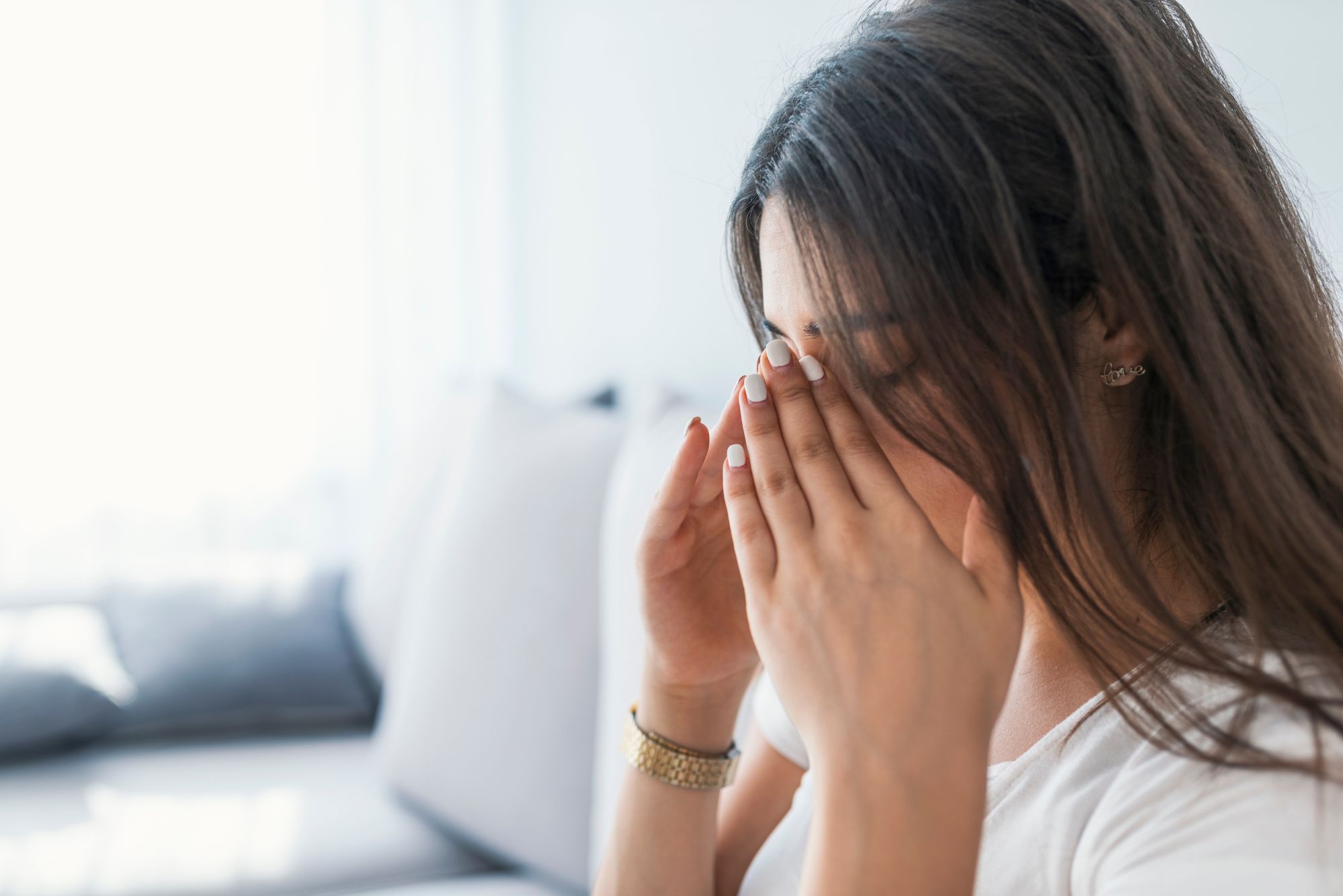 A woman with a sinus pressure headache holds her nose in pain.