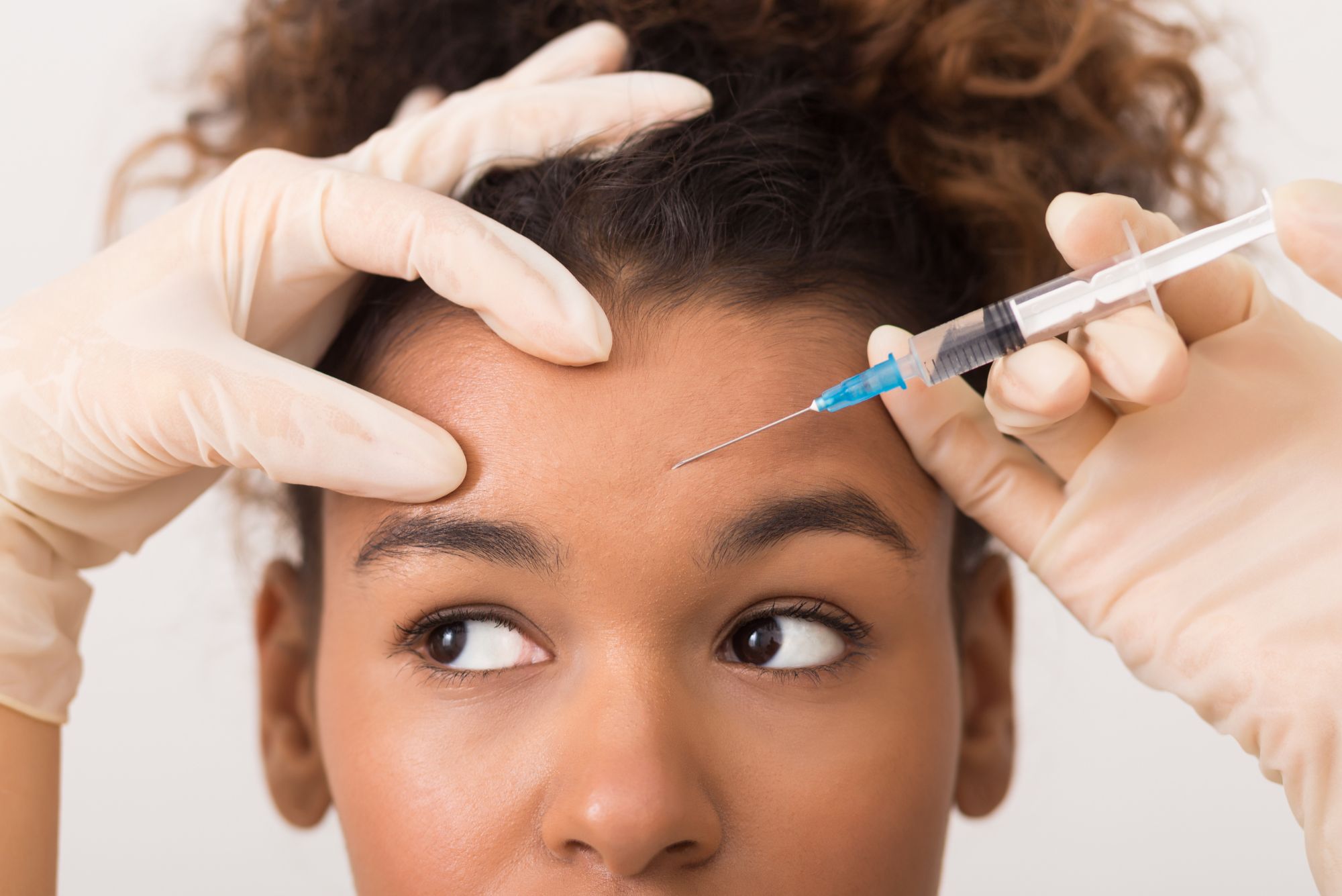 A young woman receives botox in her forehead after reading about the 3 botox danger zones.