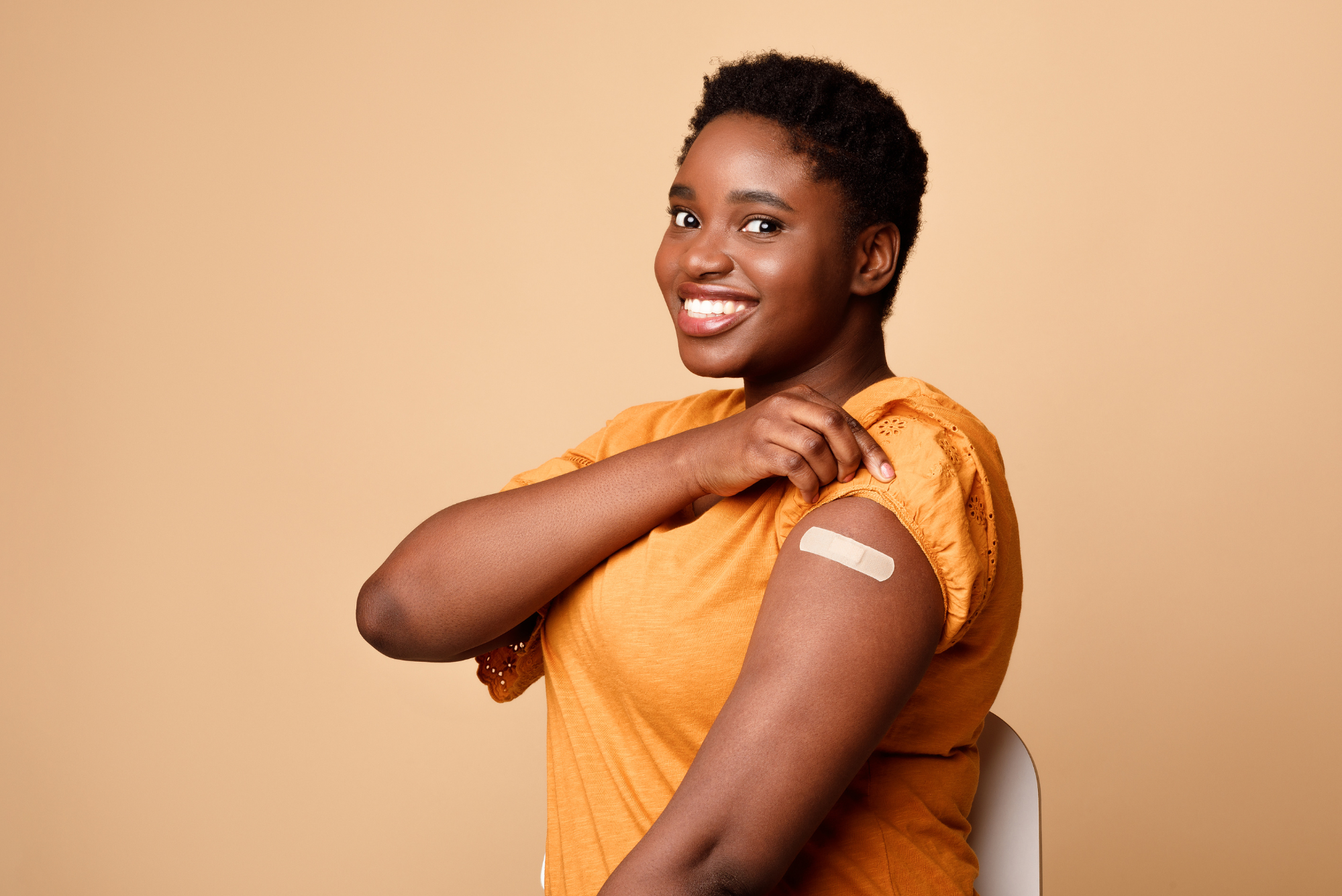 A woman with short hair smiles and shows off her bandaid from receiving her COVID-19 vaccine after her botox treatment.