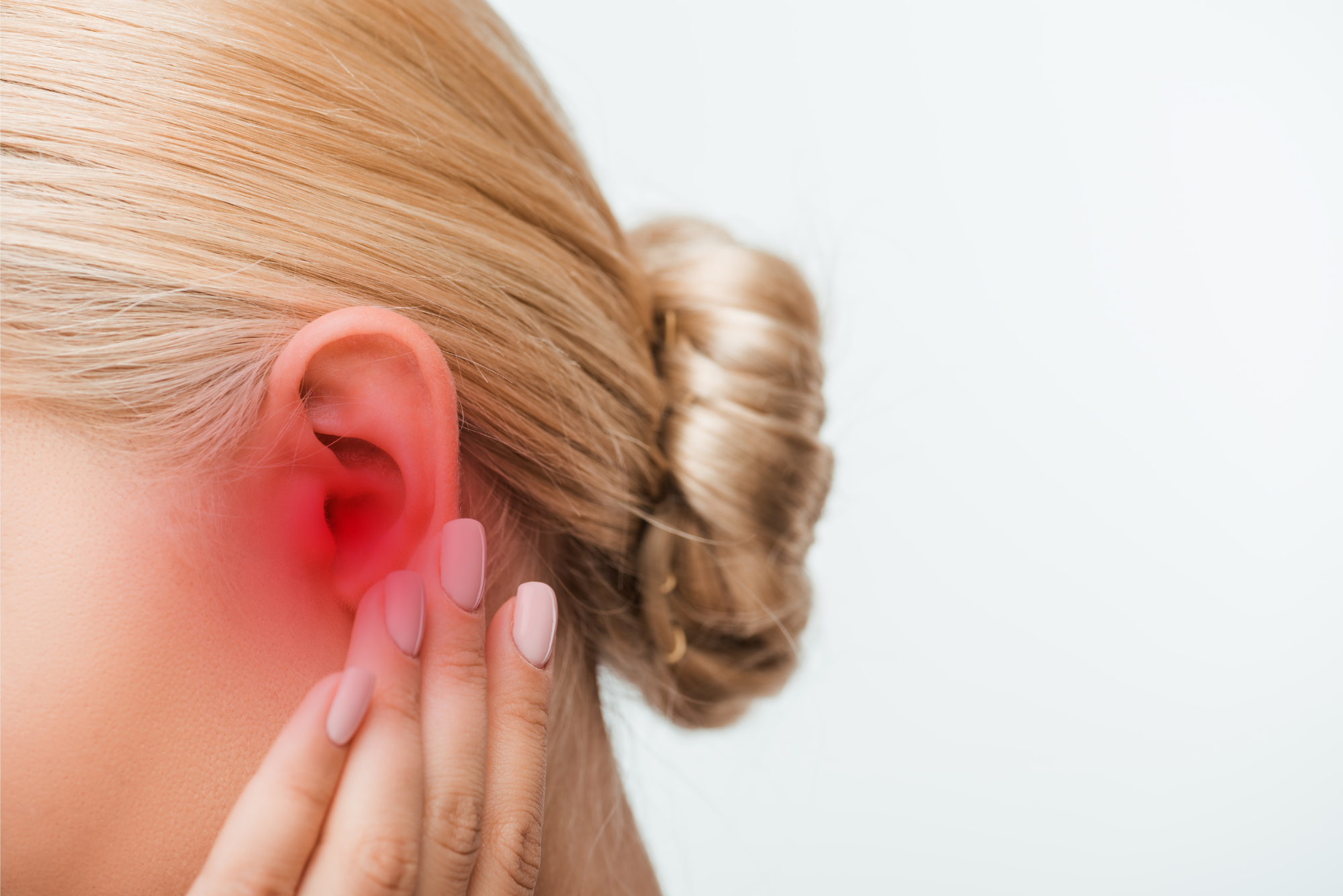 A woman holds her painful ear, wondering when she should see her doctor.