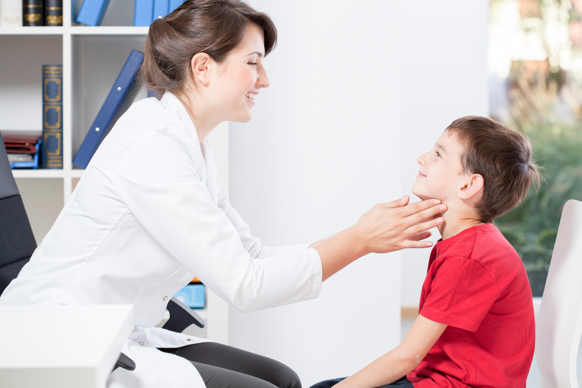 An ENT specialist examines a young boy's swollen lymph nodes to prepare for a lymph node excision procedure.