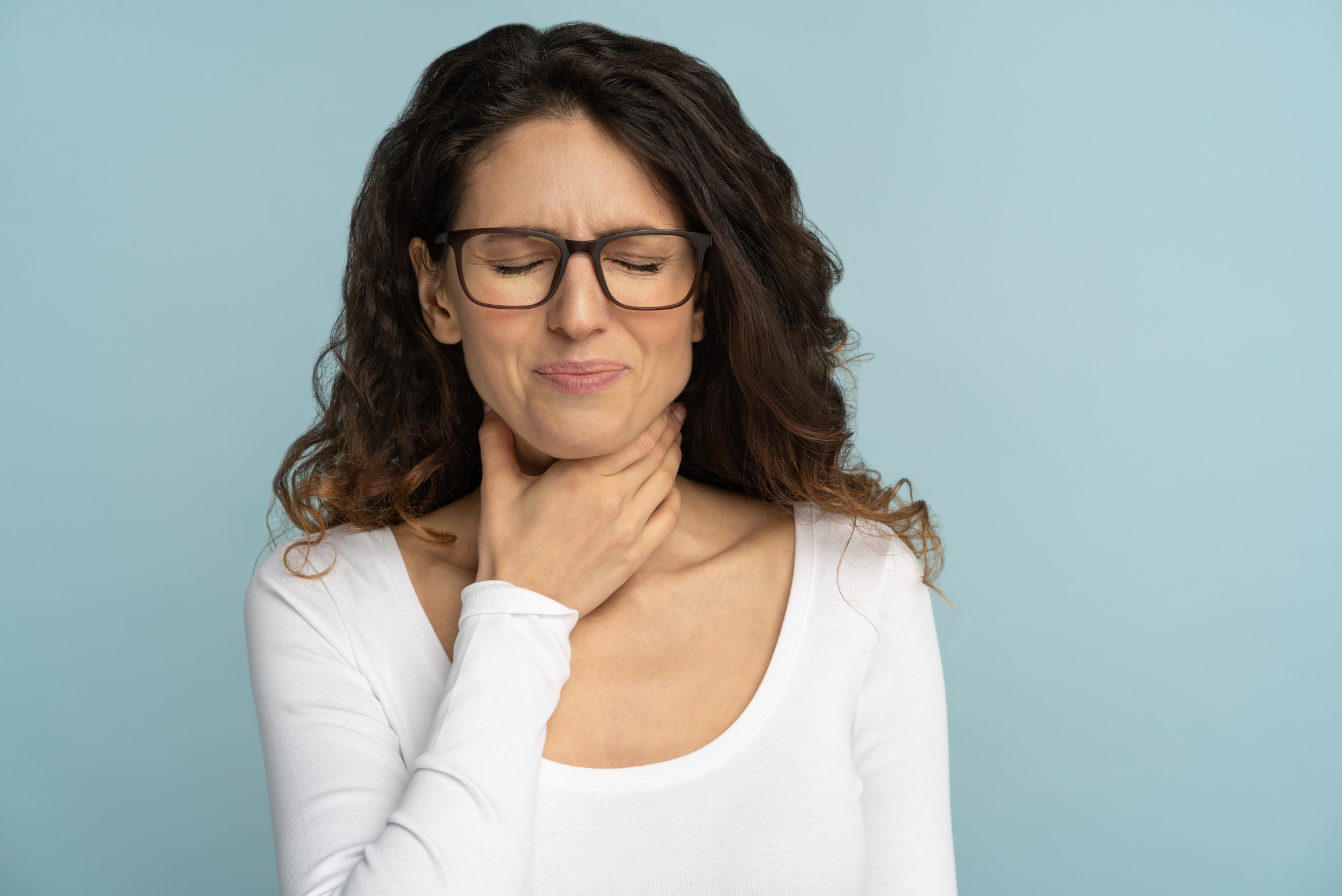 A woman who has had trouble talking holds her throat with her hands before getting vocal cord injections.