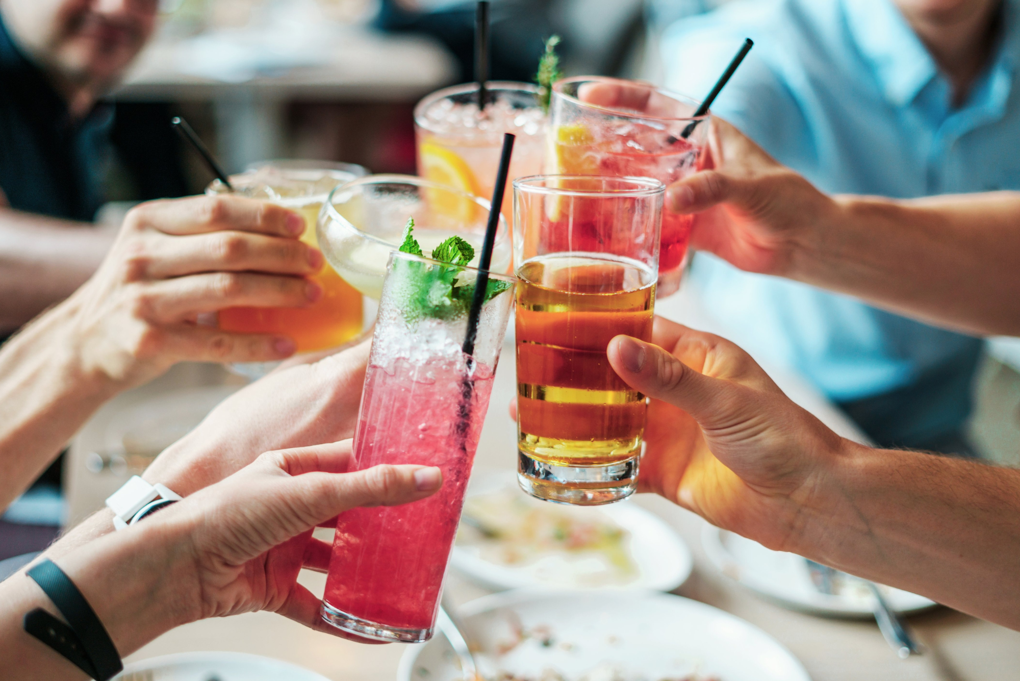 A group of friends clinks their drinks together at a restaurant after learning you can drink after botox.