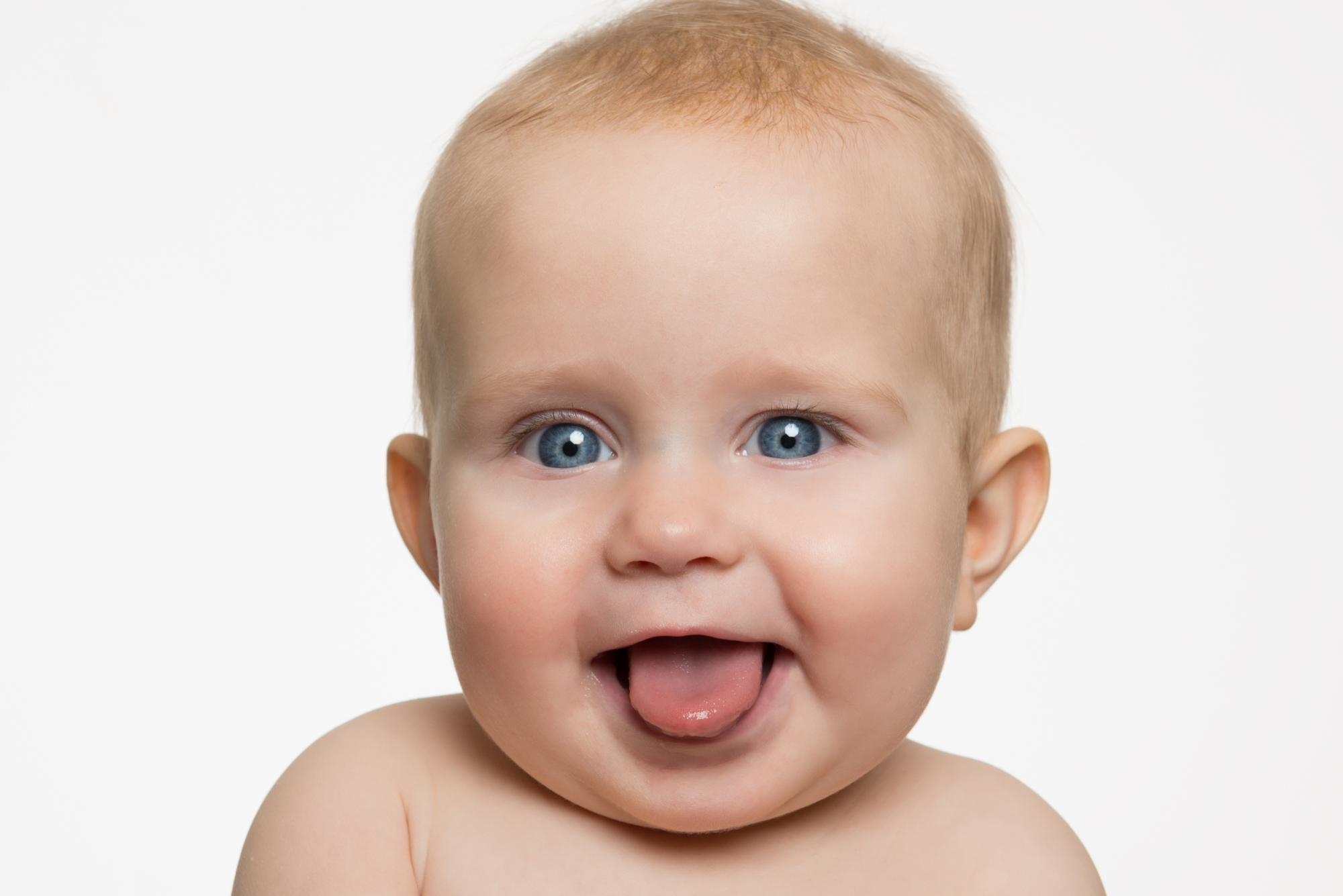 A baby smiles with his tongue out after his parents had a frenotomy performed to fix his tongue tie.