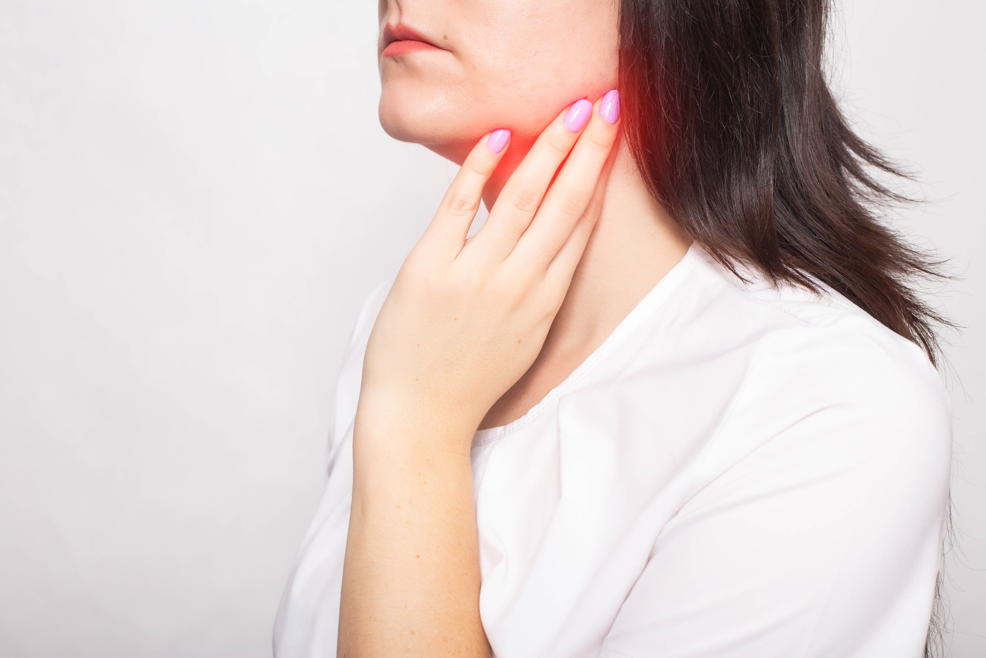 A woman touches her neck in the general location of her parotid gland.