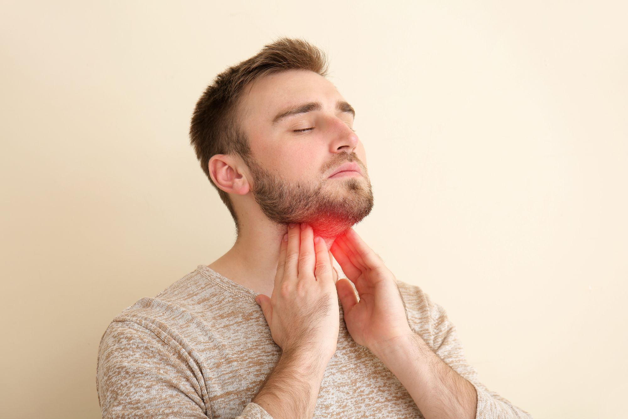 A man holds his neck where his submandibular gland is located before getting a submandibular gland excision.