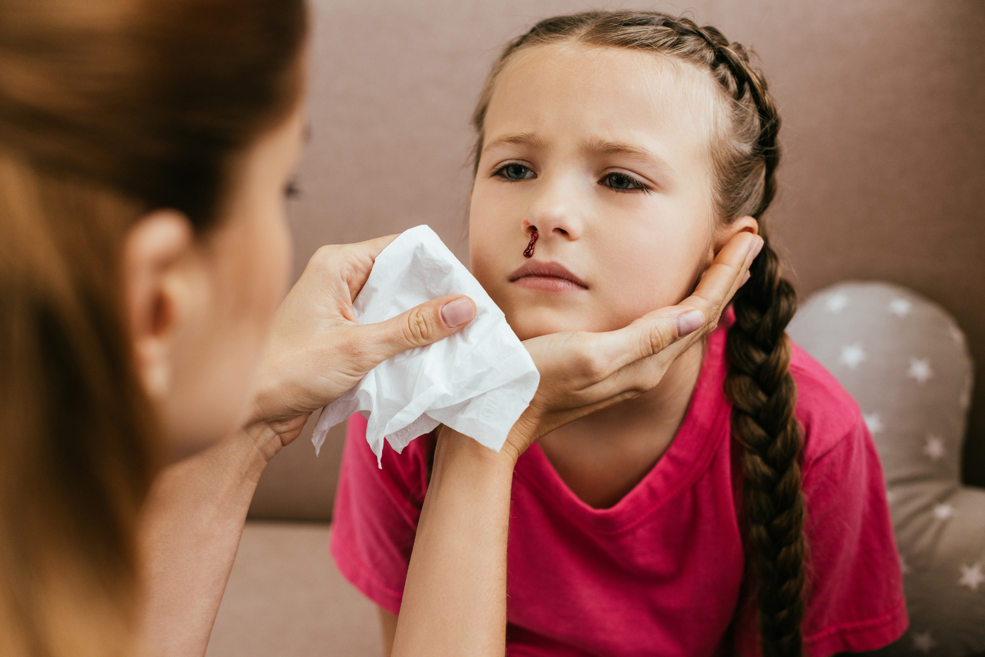 A little girl with chronic nose bleeds needs to get her nose cauterized, but for now has her nose wiped off by her mother.